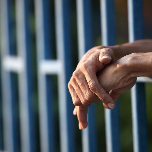 A Person's Hands Sticking Out of a Jail Cell.